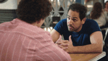 two men are sitting at a table with their hands folded