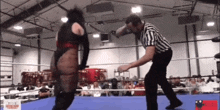 a referee is standing in the middle of a wrestling ring .
