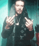 a man wearing a louis vuitton scarf giving the middle finger