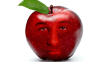 a red apple with a green leaf on top has a man 's face painted on it