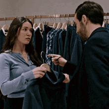 a man and a woman are in a store looking at clothes