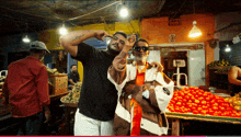 two men are posing for a picture in front of a vegetable stand