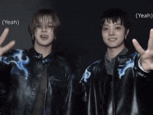 two young men are giving the peace sign and one of them is wearing a black jacket