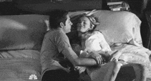 a man and a woman are laying in bed and kissing .