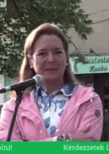 a woman in a pink jacket is standing in front of a microphone .