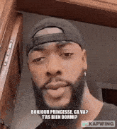 a man with a beard wearing a baseball cap and earrings says bonjour princesse ca va ?