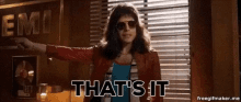 a woman wearing sunglasses is standing in front of a window and says that 's it .