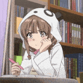 a girl wearing a panda hoodie is writing on a notebook