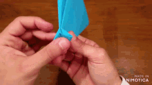 a person is holding a piece of blue paper in their hands with the words made in animatica in the corner