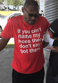 a man wearing a red t-shirt that says if you can 't name my hoes then don 't say got them
