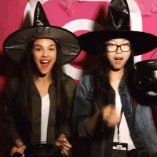 two women wearing witch hats are standing next to each other .