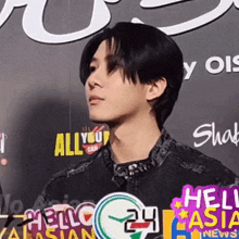 a young man stands in front of a wall that says hello 24 asia