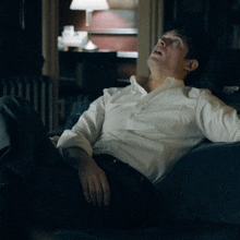 a man in a white shirt is sitting on a couch