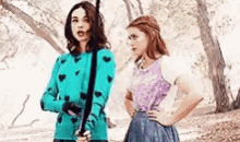 two women are standing next to each other in a park . one is holding a sword .