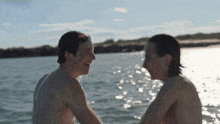 two men are sitting in the water laughing and looking at each other