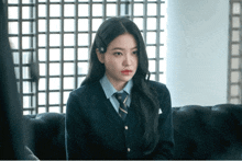 a woman in a school uniform sits on a couch