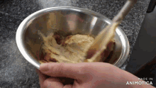 a person is mixing something in a metal bowl which says made in animatica on the bottom