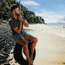 a man sitting on a tire swing on the beach