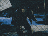a man behind a chain link fence with his mouth open and his eyes closed