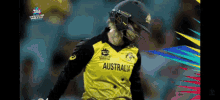 a cricket player wearing a helmet and a yellow australia jersey