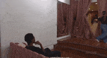 a man sits on a couch in front of a mirror with the word zeus on the bottom