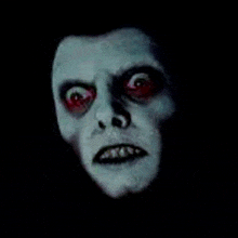 a close up of a face with red eyes and teeth