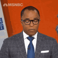 a man wearing glasses and a suit with msnbc written on the bottom