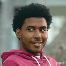 a close up of a man wearing a pink hoodie and smiling .