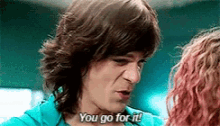 a man in a blue shirt is talking to a woman with pink hair .