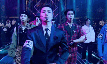 a group of men are standing on a stage in front of a crowd . one of the men is wearing a suit and tie .