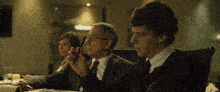 a man in a suit and tie is sitting at a table with other people