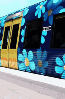 a blue and yellow train with blue flowers painted on the side