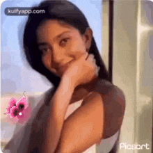 a woman is smiling with her hand on her chin and a pink butterfly is behind her .