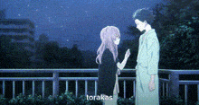 a man and a girl are standing next to each other on a balcony at night .