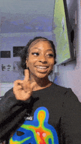 a woman wearing a shirt that says ' iowa ' on it is smiling and giving a peace sign