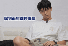 a man wearing a white t-shirt with a fox on it sits on a couch