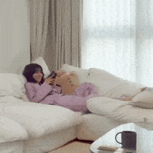 a woman is laying on a white couch holding a stuffed animal