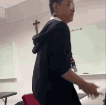 a young man is standing in a classroom in front of a whiteboard .