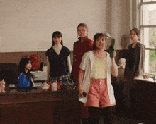 a group of women are standing in a room and one of them is holding a green cactus