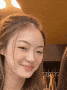 a close up of a woman smiling and looking at the camera in a room .