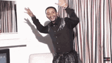a man in a black shirt is standing in front of a striped curtain ..