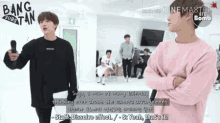 a man in a pink sweater is standing next to another man in a black shirt .