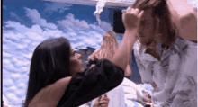 a man and a woman are standing next to each other and the woman is touching the man 's face .