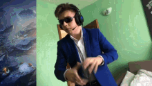 a man wearing headphones and sunglasses is dancing in front of a green wall