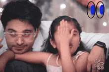 a little girl covering her eyes with a man 's arm and a sc logo