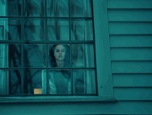 a woman looks out of a window with a blue background