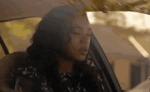 a woman is sitting in the driver 's seat of a car and talking on a cell phone .