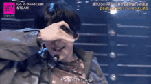 a man covering his face with his hand while singing go in blind & team