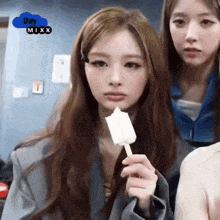 a girl is holding an ice cream cone in her hand while another girl looks on .