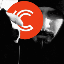 a man holding a red circle with a white letter c on it